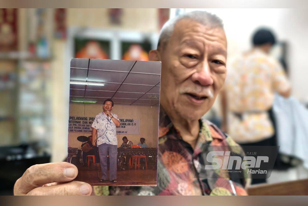 Ng Kim Soy reminisces, holding a photo of himself singing at an event during his younger days, a testament to his lifelong passion for music.
