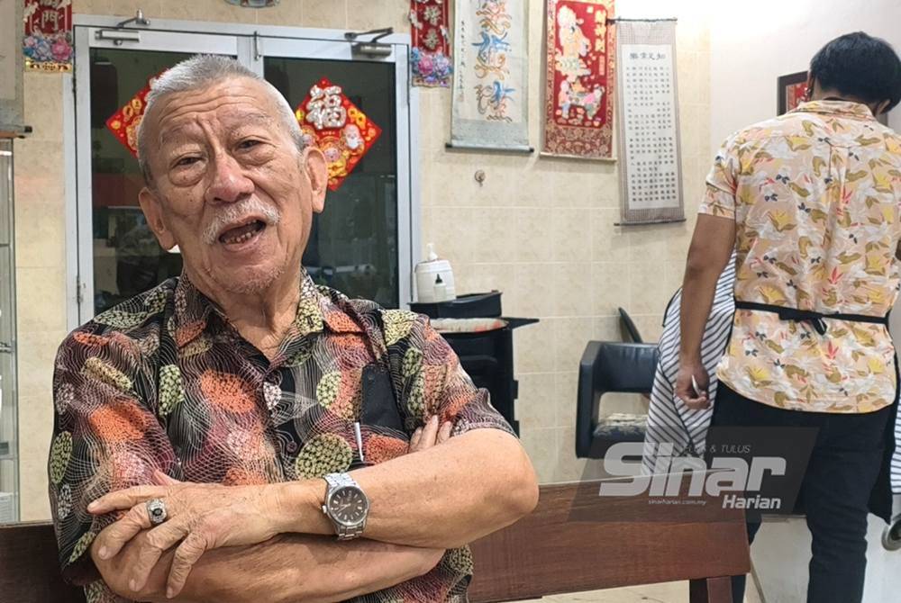 Ng Kim Soy reminisces, holding a photo of himself singing at an event during his younger days, a testament to his lifelong passion for music.