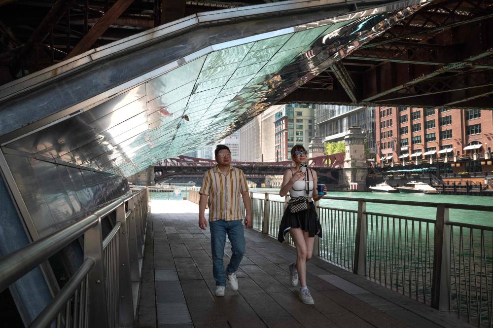 People cool off in the shade along the Riverwalk as temperatures climbed into the mid-90s on June 23, 2025 in Chicago, Illinois. (Photo by SCOTT OLSON / GETTY IMAGES NORTH AMERICA / Getty Images via AFP)