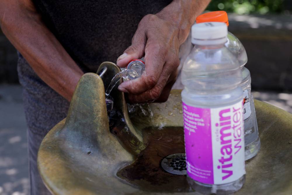 A man fills bottles with water in New York City on June 24, 2025. A potentially life-threatening heat wave enveloped the eastern third of the United States on June 23 impacting nearly 160 million people, with temperatures this week expected to reach 102 degrees Fahrenheit (39 degrees Celsius) in the New York metropolitan area. Dangerously high temperatures are forecast through midweek in Washington, Baltimore, Philadelphia, New York City and Boston. (Photo by Leonardo Munoz / AFP)