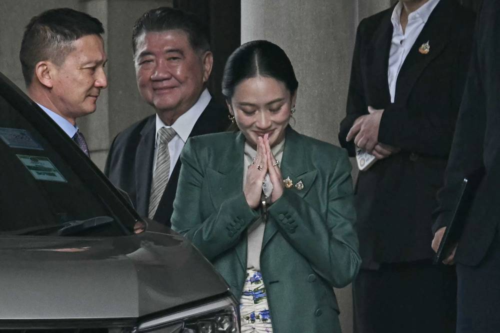 Thailand's Prime Minister Paetongtarn Shinawatra (C) gestures next to Thailand's Deputy Prime Minister Phumtham Wechayachai (2nd L) after a press conference following her suspension by the country's Constitutional Court at Government House in Bangkok on July 1, 2025. Thai Prime Minister Paetongtarn Shinawatra was suspended by the country's Constitutional Court, as it opened a probe into her conduct in a diplomatic spat with Cambodia. (Photo by Lillian SUWANRUMPHA / AFP)