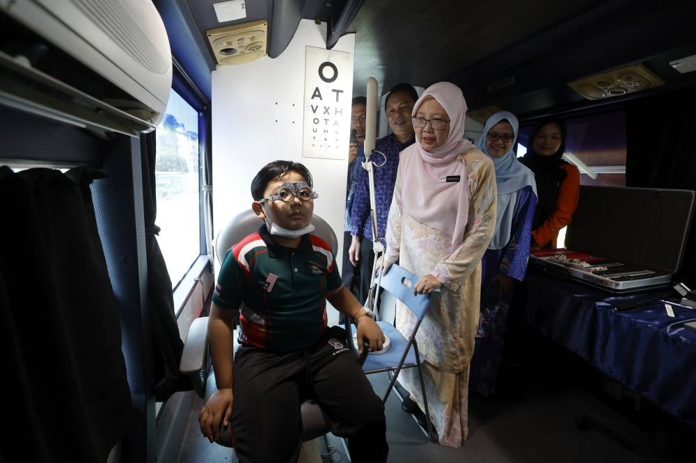 Minister in the Prime Minister’s Department (Federal Territories), Datuk Seri Dr Zaliha Mustafa (right) with student, Muhammad Harith Mohd Syimir, 8, undergoes an eye examination at the Malaysia UiTM Mobile Optometry Clinic after officiating the Mata Hati Wilayah 2025 Program at SK Seri Bintang Utara, Cheras, today. - Bernama photo
