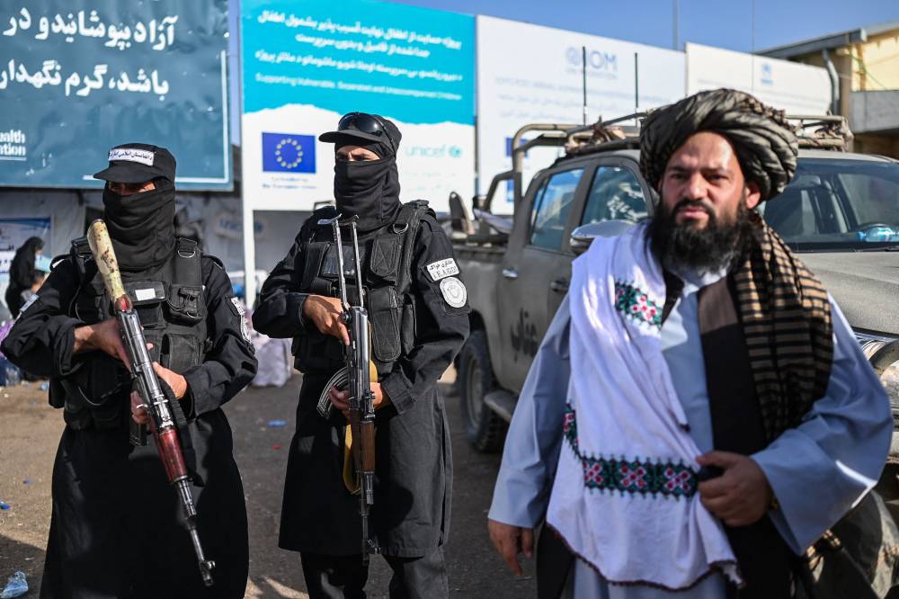 Taliban security personnel stand guard as Afghan refugees arrive at the Islam Qala border crossing between Afghanistan and Iran after their deportations from Iran, on June 27, 2025. (Photo by Wakil Kohsar / AFP)