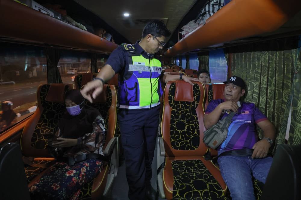 Zamri (centre) monitors the use of seat belts by bus passengers during the Ops Pemakaian Tali Pinggang Keledar Bas Ekspres dan Persiaran in Chendering, last night. - Bernama photo