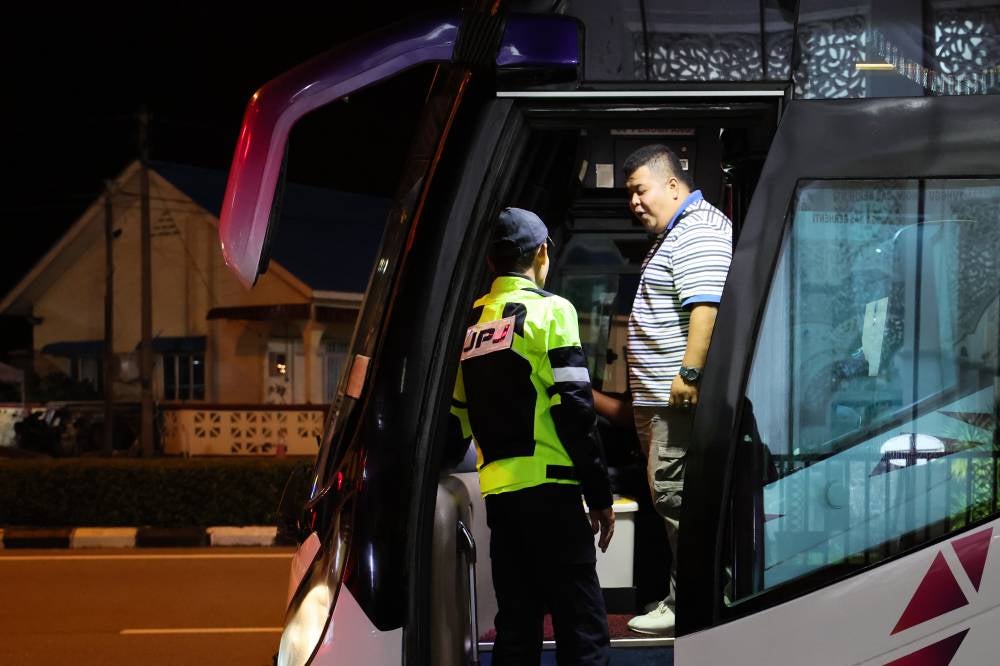 Road Transport Department (JPJ) personnel monitor the use of seat belts by bus drivers and passengers during the Ops Pemakaian Tali Pinggang Keledar Bas Ekspres dan Persiaran in Chendering, last night. - Bernama photo
