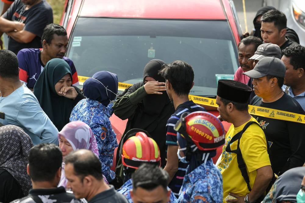 Some family members and acquaintances could not hold back their grief after seeing the six bodies found inside a car submerged in Sungai Korok, near Jitra today. Photo by Bernama