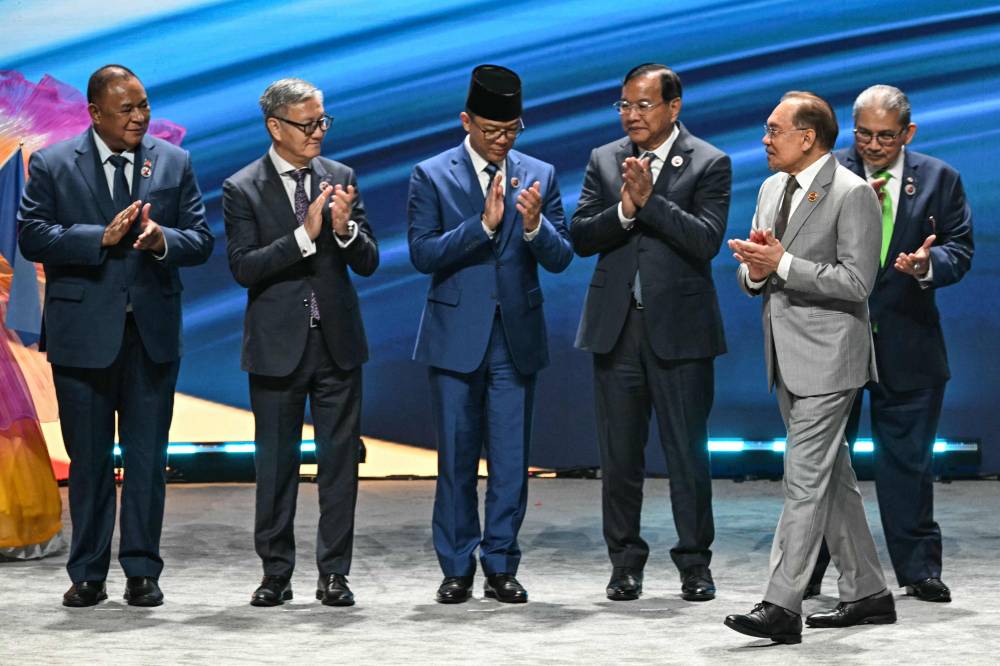 (L-R) East Timor Foreign Minister Bendito dos Santos Freitas, Laos Minister of Affairs Thongsavanh Phomvihane, Indonesia's Foreign Minister Sugiono, Cambodia's Foreign Minister Prak Sokhonn, Malaysia's Prime Minister Anwar Ibrahim and Brunei's Minister of Foreign Affairs Erywan Yusof applaud after posing for the group photo during the opening ceremony of the 58th Association of Southeast Asian Nations (ASEAN) Foreign Ministers’ meeting and related meetings at the Convention Centre in Kuala Lumpur on July 9, 2025. (Photo by MOHD RASFAN / AFP)