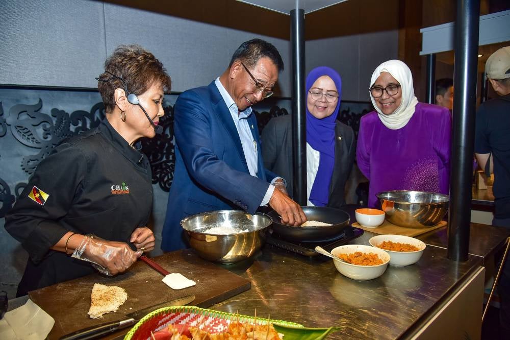 Sarawak Minister of Tourism, Creative Industry and Performing Arts Datuk Seri Abdul Karim Rahman Hamzah (second from left) prepares a traditional Sarawak dish called Tumpik, guided by Chef Laura Bara Sim during the launch of Serumpun Sarawak at a hotel recently. Photo by Bernama