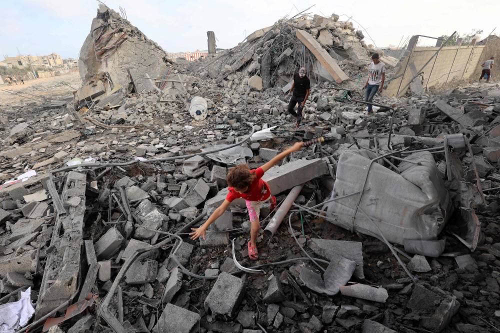 A Palestinian girl finds his way amid the rubble of a building hit in an Israeli strike in the Bureij refugee camp in the central Gaza Strip on July 10, 2025. - (Photo by EYAD BABA / AFP)
