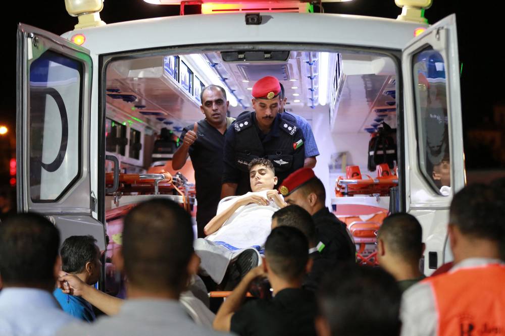 Members of the Jordanian security forces carry a young Palestinian patient out of an ambulance on his way to receive treatment at a hospital in Amman, after being evacuated from the Gaza Strip on July 16, 2025. - (Photo by KHALIL MAZRAAWI / AFP)