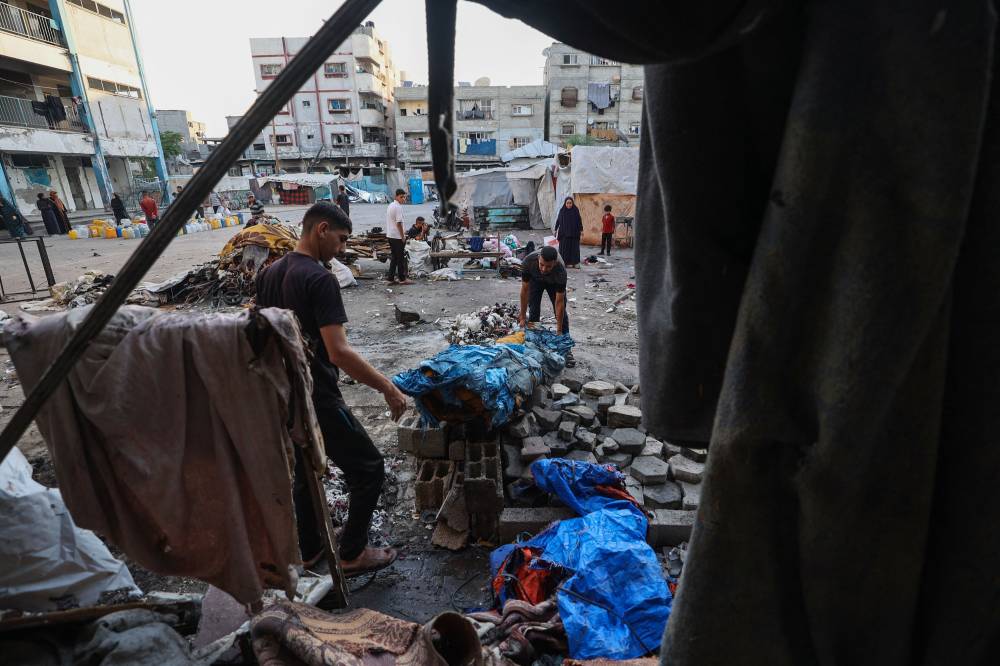 Palestinians salvage items from the debris of a tent which was hit in Israeli strikes a day earlier, at the UNRWA-run Abou Helou school for girls at the Bureij refugee camp in the central Gaza Strip on July 17, 2025. (Photo by Eyad BABA / AFP)