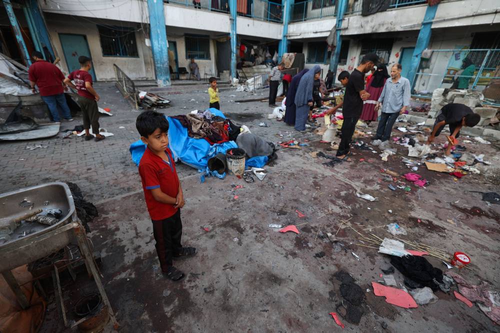 Palestinians salvage items from the debris of a tent which was hit in Israeli strikes a day earlier, at the UNRWA-run Abou Helou school for girls at the Bureij refugee camp in the central Gaza Strip on July 17, 2025. (Photo by Eyad BABA / AFP)
