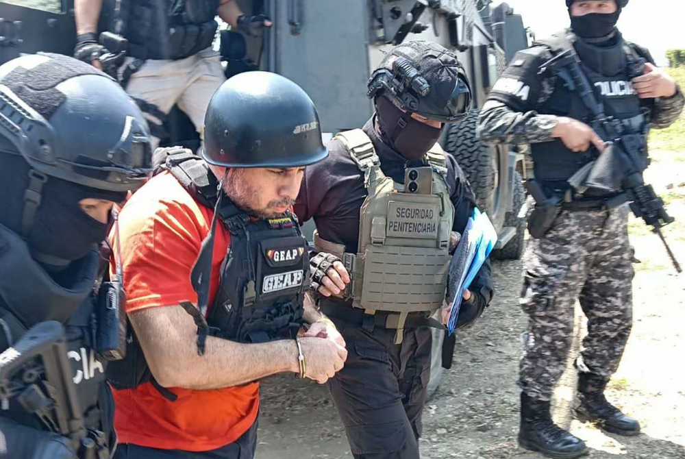 Handout picture released by the Ecuadorean Prison Authority SNAI shows drug trafficker Adolfo Macias being escorted out of La Roca prison to be extradited to US in Guayaquil on July 20, 2025. The Ecuadoran government on July 20, 2025, extradited Macias, alias "Fito," to the US, a month after he was recaptured following a 2024 escape from a maximum security penitentiary, the country's prison authority said. (Photo by Handout / SNAI / AFP)