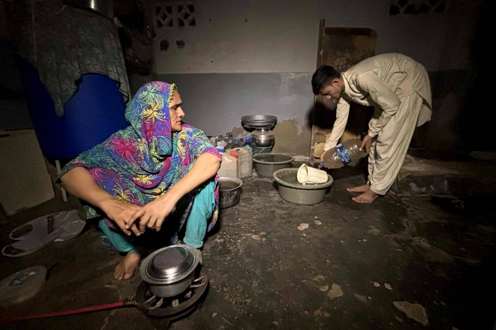 In this photograph taken on June 19, 2025, Maryam Suleman (L) and her son Ahmed Raza, residents of Lyari work in kitchen in their house in Karachi, both not registered with National Database and Registration Authority. - (Photo by Rizwan Tabassum / AFP)