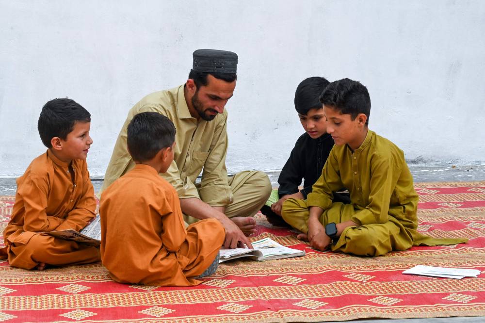 In this photograph taken on June 15, 2025, Muhammad Haris (C), teaches his children and nephews in their home at Shaikh Mal Khel village, in Landi Kotal town in Khyber-Pakhtunkhwa province. - (Photo by Abdul Majeed / AFP)