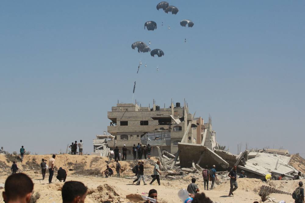 A military transport aircraft drops humanitarian aid over the northern Gaza Strip, on July 27, 2025. Jordanian and Emirati planes dropped food into Gaza on July 27, as Israel began a limited "tactical pause" in military operations to allow the UN and aid agencies to tackle a deepening hunger crisis. (Photo by BASHAR TALEB / AFP)