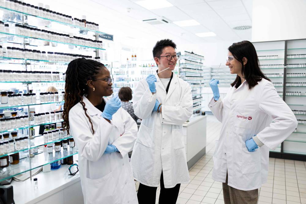 Junior perfumers (L-R) Attiya Setai, Shangyun Lyu and Alicia de Benito Cassado hold smell strips which are used to evaluate fragrances in a mixing room at the Symrise company, where perfume oil formulas are developed, in Holzminden, central Germany. Photo by Michael Matthey/AFP