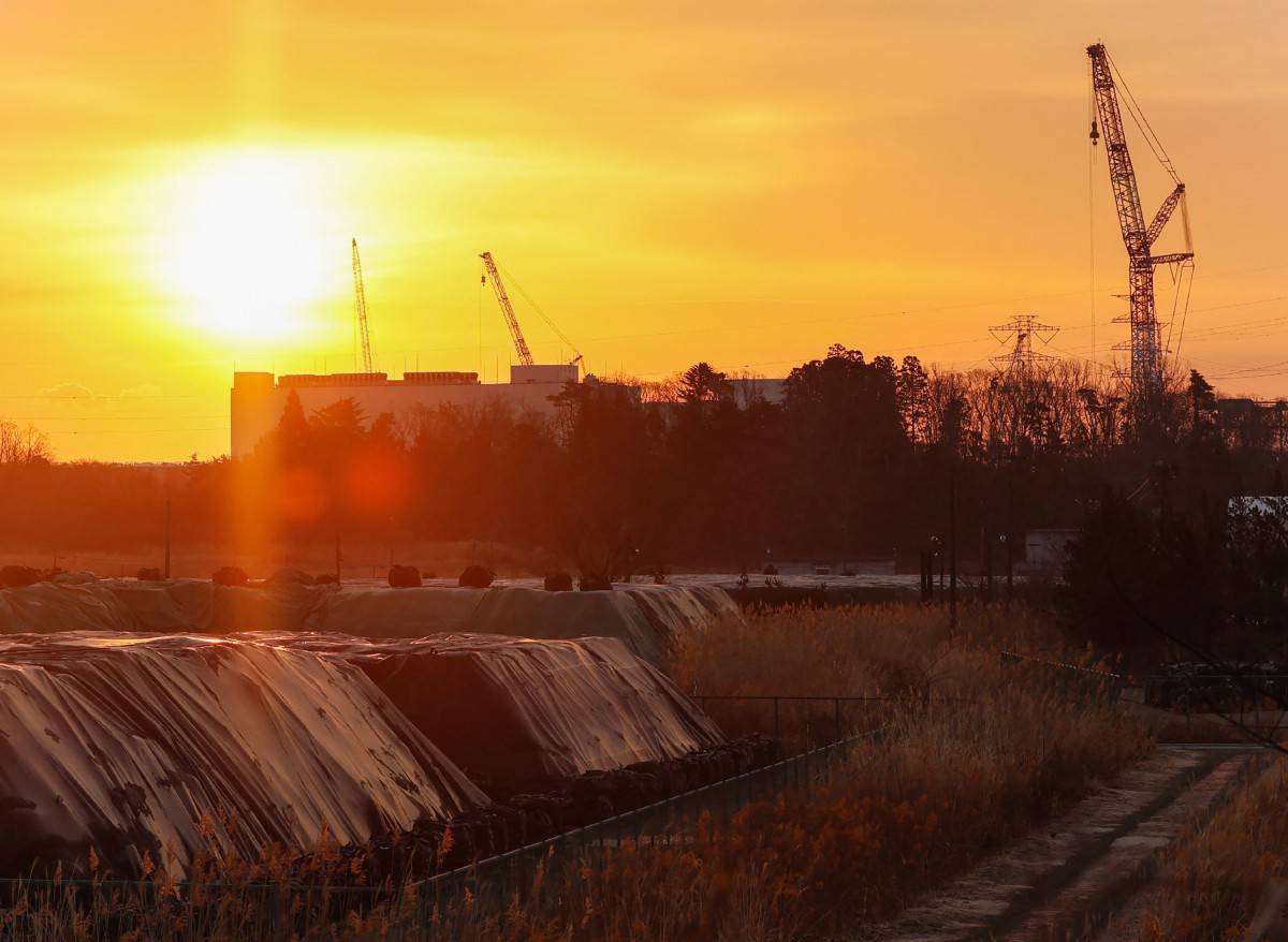 The sun rises behind the Fukushima Daiichi Nuclear Power Plant in Okuma, Fukushima prefecture on March 11, 2025, on the 14th anniversary of the magnitude 9.0 earthquake which triggered a tsunami and nuclear disaster. (Photo by JIJI Press / AFP) 
