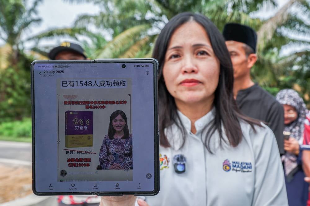 Deputy Communications Minister and Kulai Member of Parliament Teo Nie Ching, shows a fake post using her image on Facebook during a media interview after attending a site visit to the flood mitigation project at Jalan Masjid, Kampung Melayu Bukit Batu, recently. Photo by Bernama