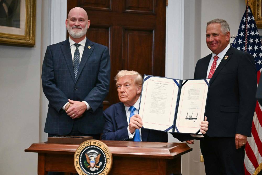 US President Donald Trump holds up the bill after signing the VA Home Loan Program Reform Act in the Roosevelt Room of the White House in Washington, DC, on July 30, 2025. The bill aims to help veterans receive improved federal assistance for home mortgages.
Also pictured, L/R, are US Representatives Derrick Van Orden, Republican from Wisconsin and Mike Bost, Republican from Illinois. (Photo by Jim WATSON / AFP)