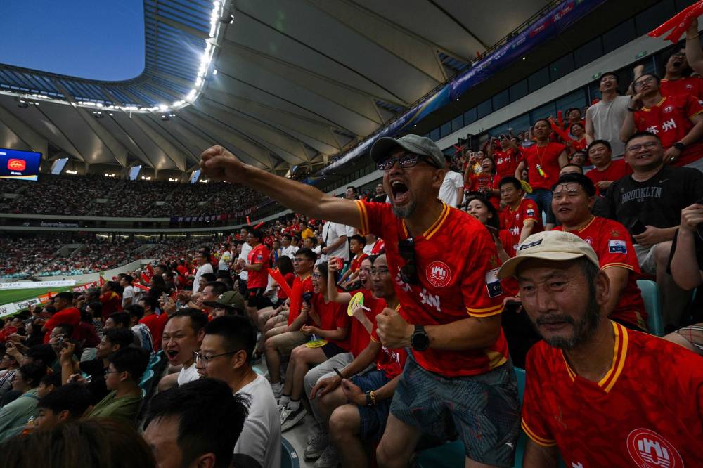 Suzhou fans watch the amateur league football match between Suzhou and Yangzhou at the Kunshan Olympic Sport Center in Kunshan, in eastern China's Jiangsu province on June 29, 2025. On a summer's day in the city of Suzhou, about 40,000 people crowded into a stadium while thousands more gathered by public screens to watch China's hottest sport -- amateur football. (Photo by Hector RETAMAL / AFP)