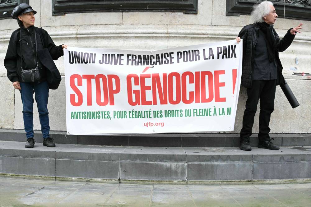 A man and a woman hold a banner during a pro-Palestinian demonstration against Israel's actions and the ongoing food shortages in the Gaza Strip and to welcome the released activists of the Freedom Flotilla vessel Handala at the Place de la Republique in Paris on July 29, 2025. - (Photo by BERTRAND GUAY / AFP)