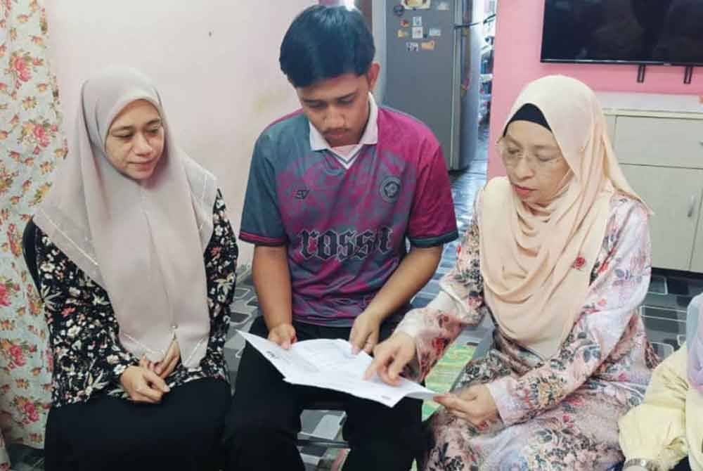 Fakhrullah and his mother showing his medical report to Zuraini (right) during a visit to their home at Flat Seri Gemilang, Alor Setar.