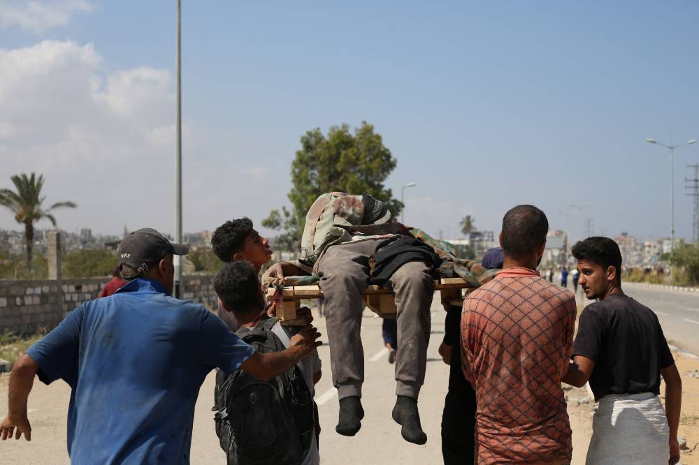 Palestinians carry a victim who was seeking food at a distribution point run by the US and Israeli-backed Gaza Humanitarian Foundation (GHF) group, on Salah al-Din road near the Nusseirat refugee camp in the central Gaza Strip on August 2, 2025. (Photo by Eyad BABA / AFP)