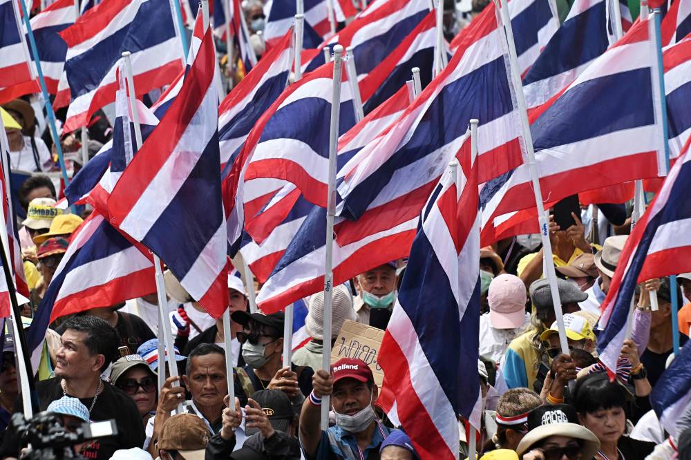Anti-government protesters hold Thai national flags during a demonstration to demand the removal of Thailand's Prime Minister Paetongtarn Shinawatra from office outside Government House in Bangkok on June 19, 2025. Paetongtarn faced mounting calls to resign on June 19 after a leaked phone call she had with former Cambodian leader Hun Sen provoked widespread anger and a key coalition partner to quit. (Photo by Lillian SUWANRUMPHA / AFP)
