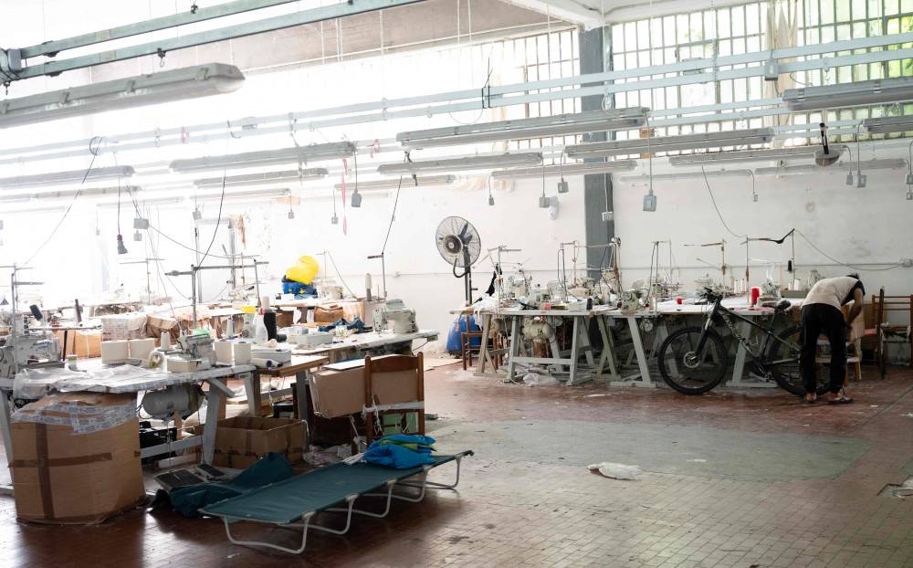 A Pakistani worker checks a bicycle during a permanent strike in a fast-fashion outlet factory owned by a Chinese company in Prato, central Italy, on August 1, 2025. Chinese groups in the district thrive on the so-called "Prato system", long rife with corruption and widely documented irregularities, particularly in the fast-fashion sector, such as labour and safety violations plus tax and customs fraud. They pop up quickly and shut down just as fast, playing a cat-and-mouse game with authorities to avoid taxes or fines. Fabric is smuggled from China, evading customs duties and taxes, while profits are returned to China via illegal money transfers. (Photo by Stefano RELLANDINI / AFP)