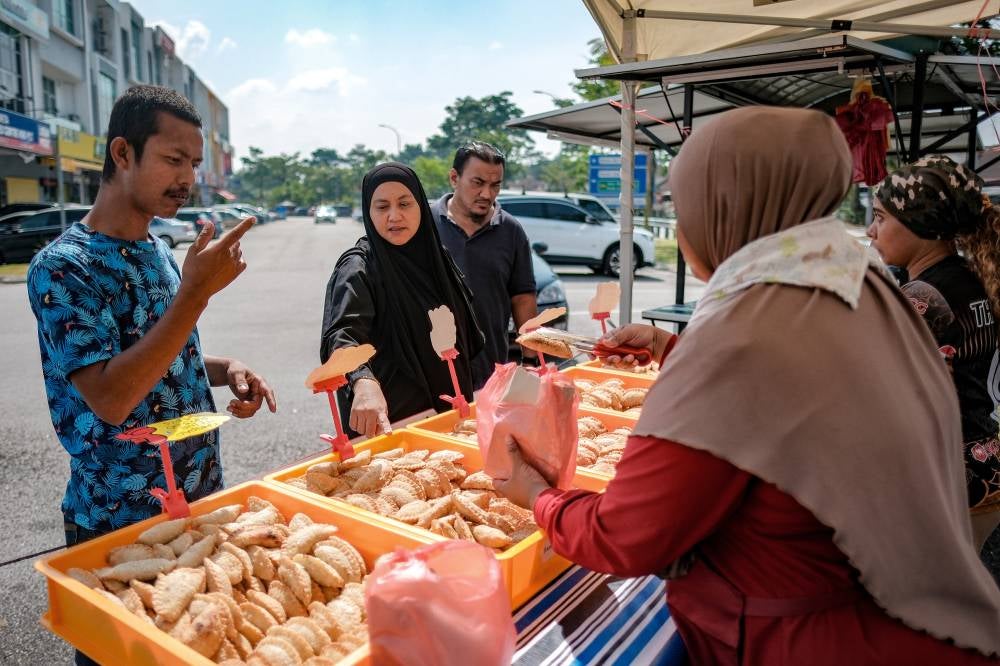 Zulkifli Ainul and Siti Nuratika communicate with customers using simple, intuitive hand gestures that are easy to understand. Photo by Bernama