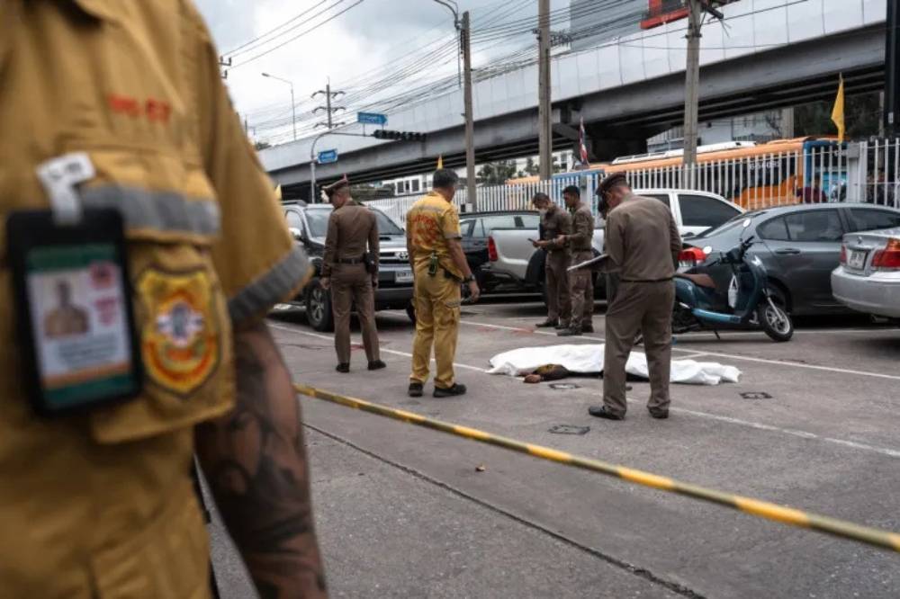 Thai police stand next to a covered body at Or Tor Kor Market in Bangkok on July 28. (Chanakarn Laosarakham/AFP)