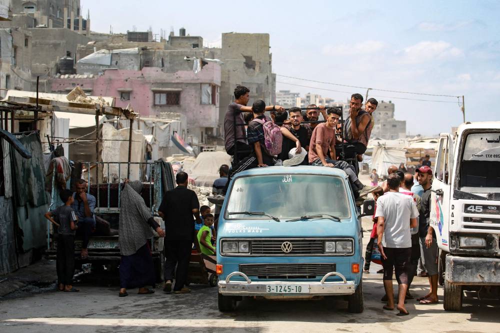 Palestinian men ride atop a van used for public transportation in Gaza City on Aug 8. Photo by Bashar Taleb/AFP