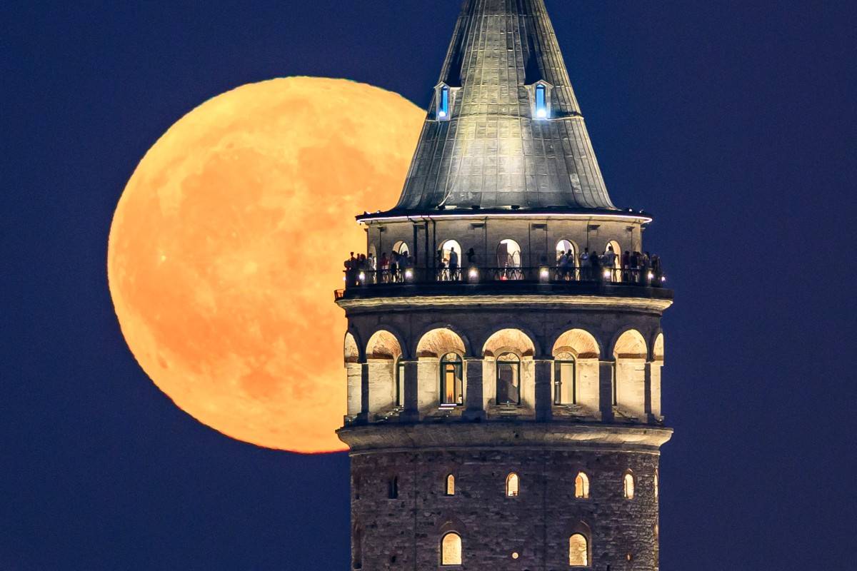 The Sturgeon moon is seen rising over Galata Tower in Istanbul, on August 9, 2025. (Photo by Yasin AKGUL / AFP)