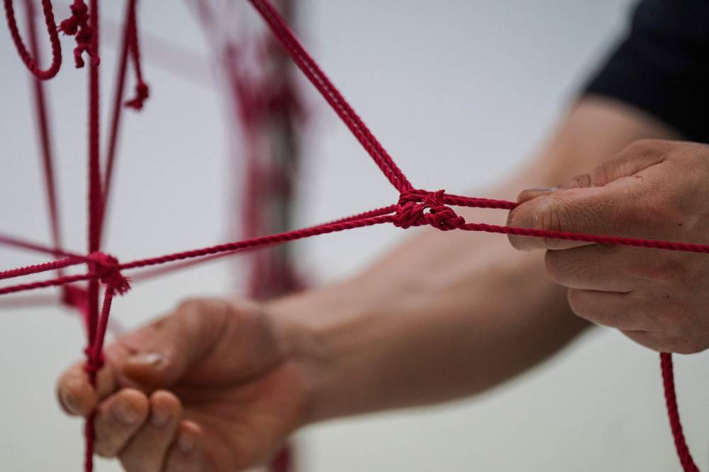 Hajime Kinoko, one of Japan's best-known artists of "shibari" or rope art, working on a human-shaped project made from rope, at his studio in Tokyo. Photo by Caroline Gardin/AFP