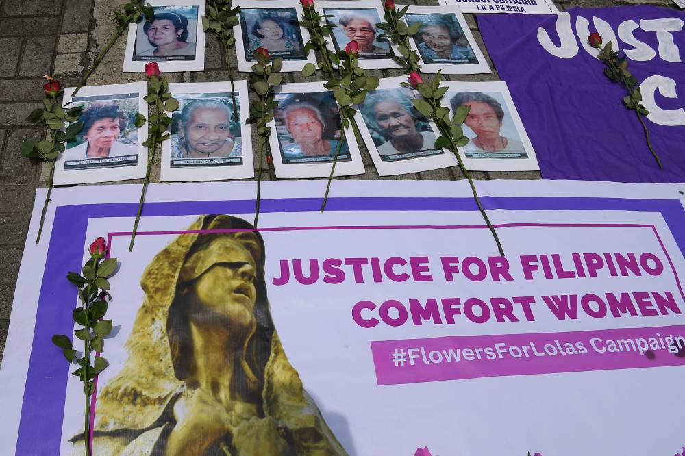 Protesters display placards and portraits of Filipina comfort women during a protest next to the former site where a statue was dedicated to comfort women along Roxas Boulevard in Manila on August 14, 2025, as part of the 80th commemoration of the end of World War II. (Photo by TED ALJIBE / AFP)