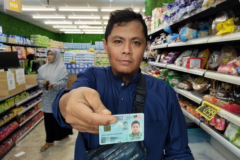 Sumbangan Asas Rahmah (SARA) recipient, Mohd Naim Mohd Zubir, 40, purchased essential items using the MyKad system, which he described as simple, with no hassle during payment and change collection, at a supermarket recently. Photo by Bernama