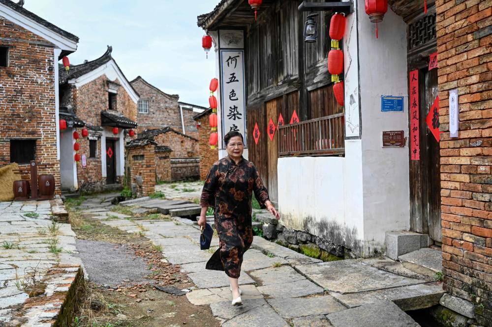 The photo taken on July 21, 2025 shows Nushu inheritor He Yuejuan walking on a street at Goulan Yao Village in Jiangyong county, southern China's Hunan province. Nushu,