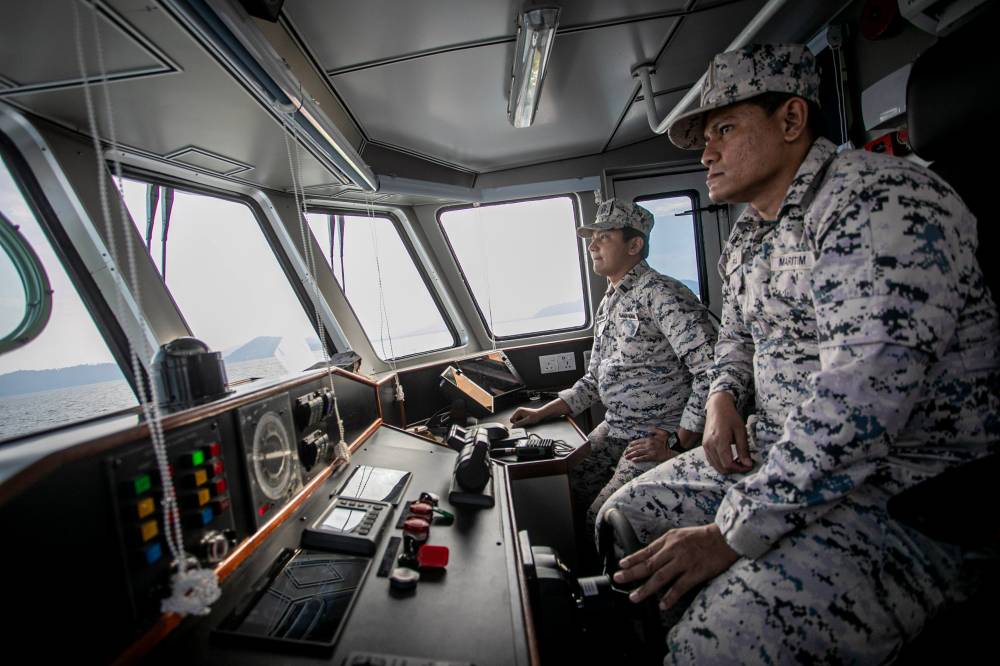Perak Malaysian Maritime Enforcement Agency (MMEA) enforcement officer Suhaime Abdul Wahab (left) with Mohd Saiful Amry Fadil (right) carrying out duties in local waters recently. Photo by Bernama