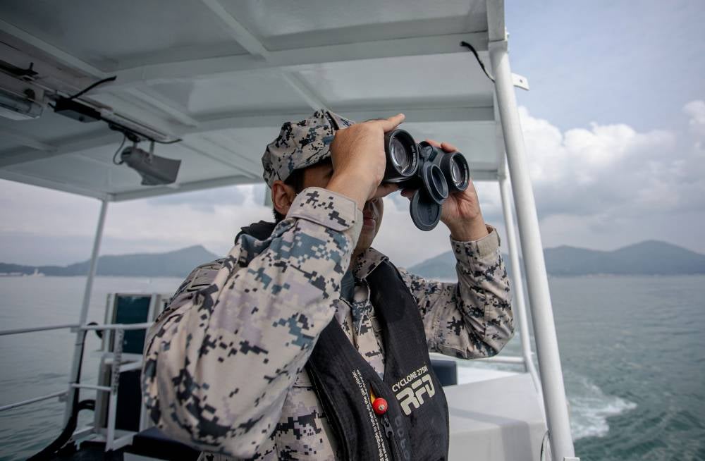 Perak Malaysian Maritime Enforcement Agency (MMEA) officer Khairul Nazrin Kamal using binoculars during a patrol in local waters recently. Photo by Bernama