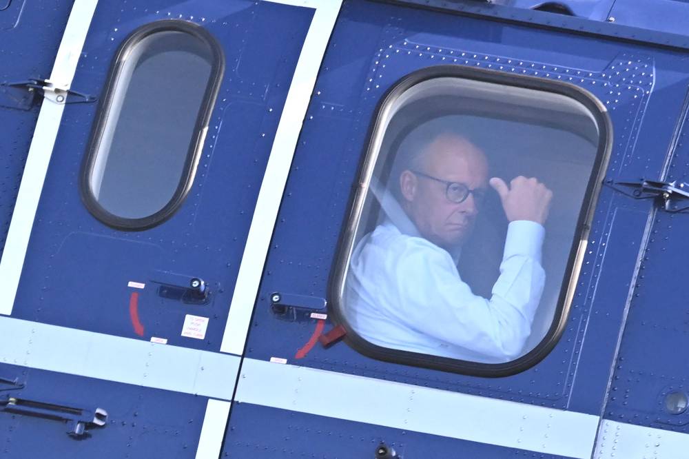 German Chancellor Friedrich Merz is seen through a window inside a helicopter to leave after the press conference with the Ukrainian President following a video conference of European leaders with the US President on the Ukraine war ahead of the summit between the US and Russian leaders, in Chancellery in Berlin, on August 13, 2025. (Photo by RALF HIRSCHBERGER / AFP)