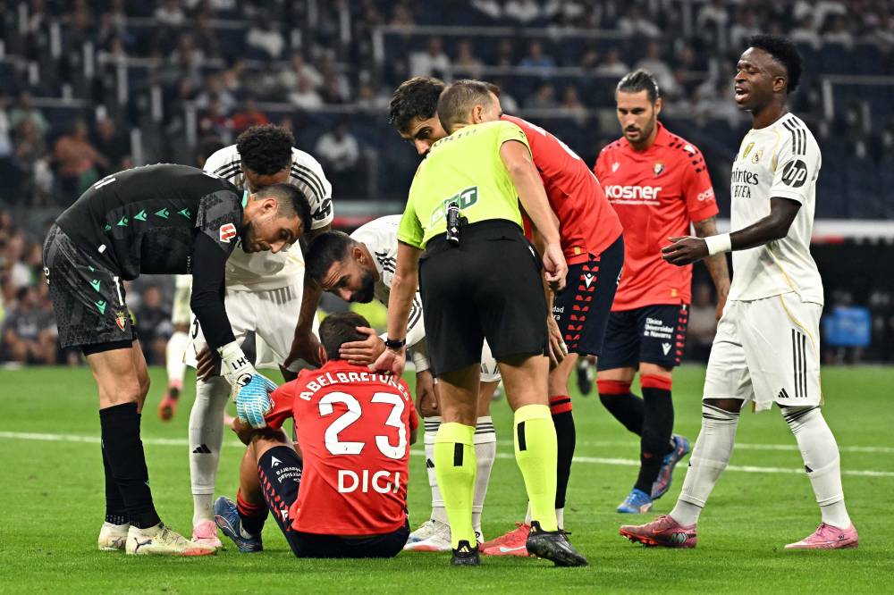 Real Madrid's Spanish defender #02 Dani Carvajal (C) checks on Osasuna's Spanish defender #23 Abel Bretones (BOTTOM) during the Spanish league football match between Real Madrid CF and CA Osasuna at Santiago Bernabeu Stadium in Madrid on August 19, 2025. (Photo by Javier SORIANO / AFP)