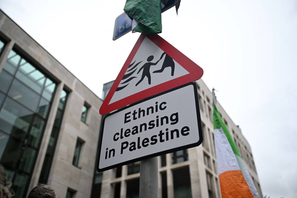 A mock road sign reading "Ethnic Cleansing in Palestine" is pictured outside Westminster Magistrates' Courts in London on August 20, 2025, where Liam O'Hanna, who performs under the stage name Mo Chara, from the Irish rap band Kneecap, is set to appear charged with a terror offence. A member of Irish rap band Kneecap was due to appear in court on Wednesday charged with a terror offence for allegedly supporting Hezbollah. (Photo by JUSTIN TALLIS / AFP)