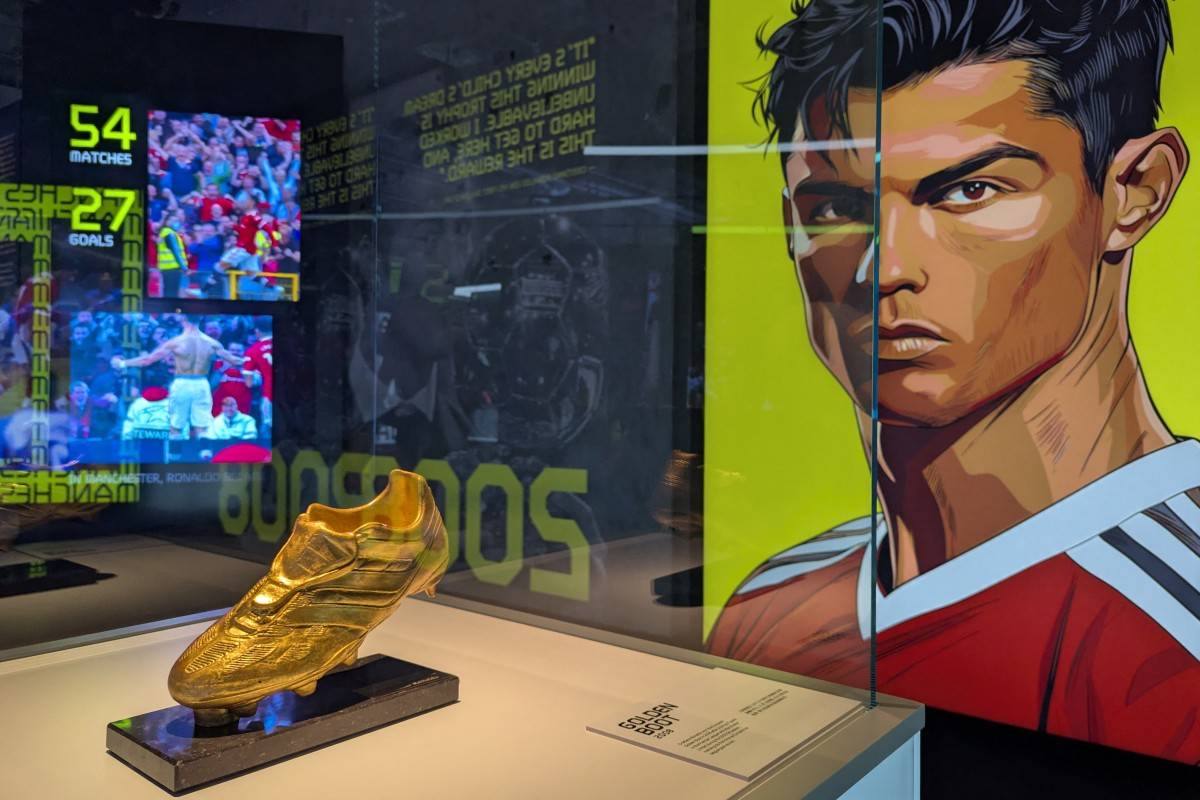 Cristiano Ronaldo's Golden Boot trophy is seen on display beside a portrait of the footballer during the opening of the CR7 LIFE Museum in Hong Kong on July 7, 2025. Hong Kong football fans queued for hours July 7 to snap pictures of Cristiano Ronaldo's trophies and jerseys at an exhibition billed as the first of its kind outside the superstar's native Portugal. (Photo by Holmes CHAN / AFP)