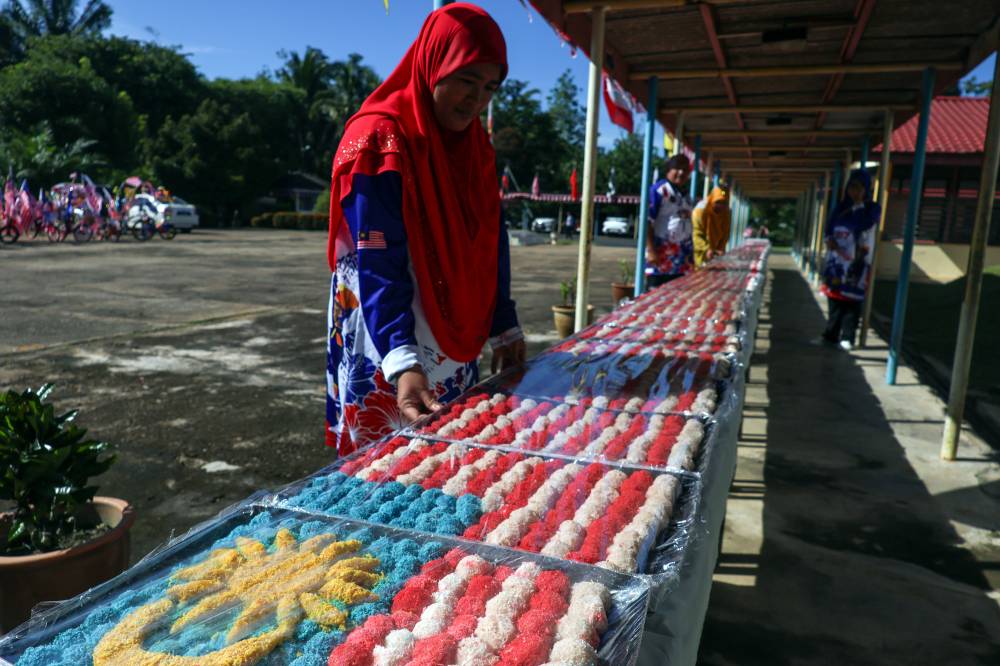 Among the servers from the Parent-Teacher Association arranging the Jalur Gemilang made from onde-onde balls during the “Cetusan Jiwa, Semarak Merdeka” programme at the Kesedar Chalil Land Development Scheme (RKT), Gua Musang, today. - Photo by Bernama