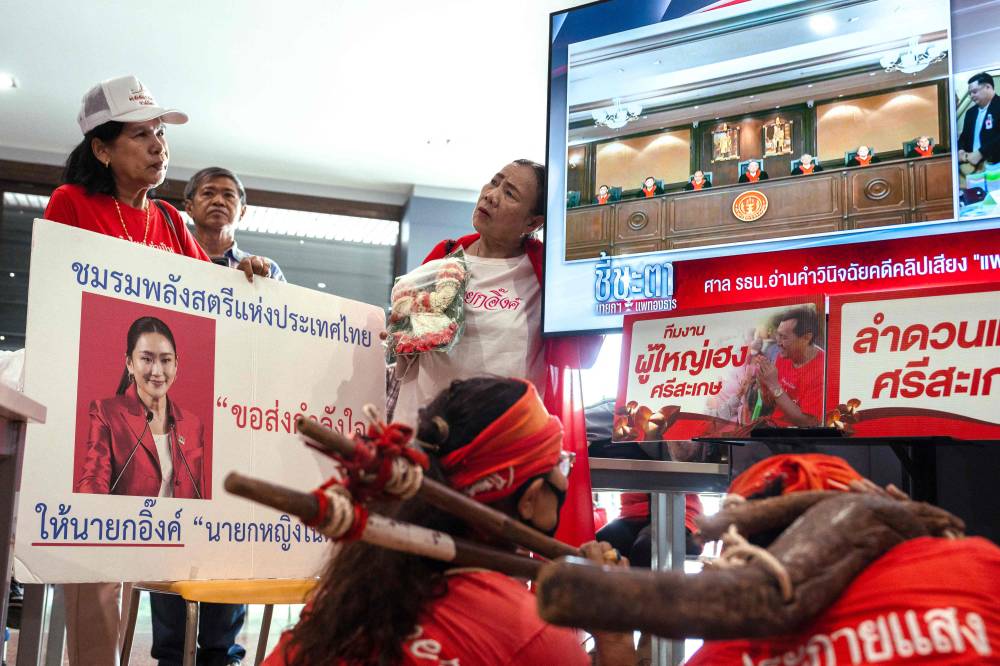 Supporters of Thailand's suspended prime minister Paetongtarn Shinawatra watch a monitor showing proceedings at the Constitutional Court, at the Pheu Thai Party headquarters in Bangkok on Aug 29. Photo by Chanakarn Laosarakham/AFP