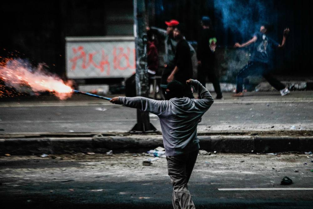 Young men face police officers after a labour union protest to demand a revision to the labor law and ways to ensure better work protection across the country near the Parliament building in Jakarta on Aug 28, 2025. - (Photo by ADITYA IRAWAN / AFP)