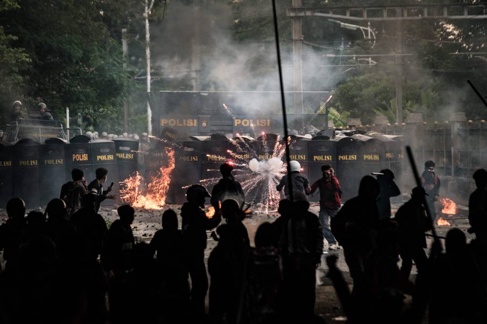 A 'Molotov cocktail' burns and a firework explodes whilst police personnel confront demonstrators during a labour union protest for improving working conditions, near the Parliament in Jakarta on Aug 28, 2025. (Photo by YASUYOSHI CHIBA / AFP)