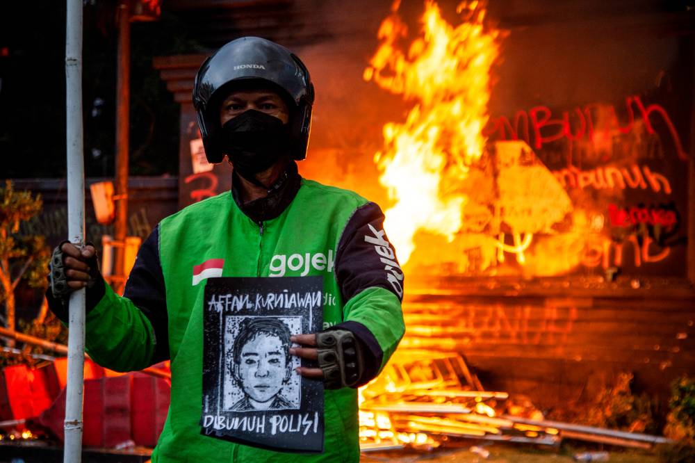 An e-hailing rider holds a portrait of the late Affan while joining a protest in front of the Jakarta Metropolitan Police Headquarters on Aug 29, 2025. Photo: AFP