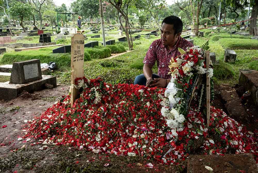 A friend prays at the grave of Affan Kurniawan in Jakarta. Photo: AFP”